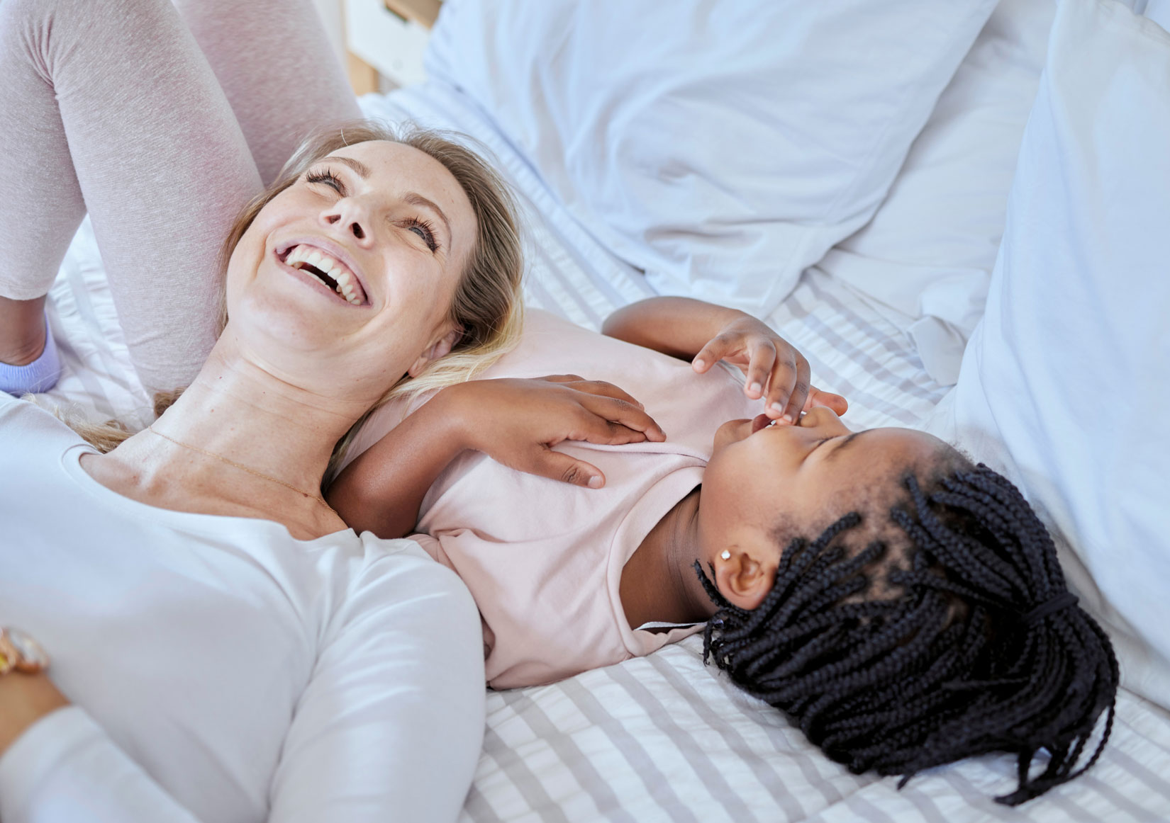 Fröhliche Mutter und Kind lächeln im Bett.