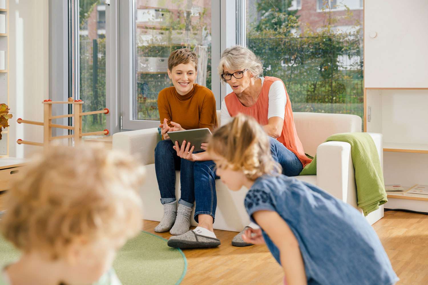 Großmutter und Enkelkinder mit Tablet zuhause.