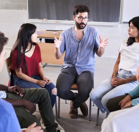 Lehrer diskutiert mit Schülern im Klassenzimmer.