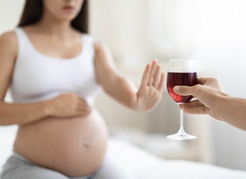 Schwangere Frau lehnt Wein ab.