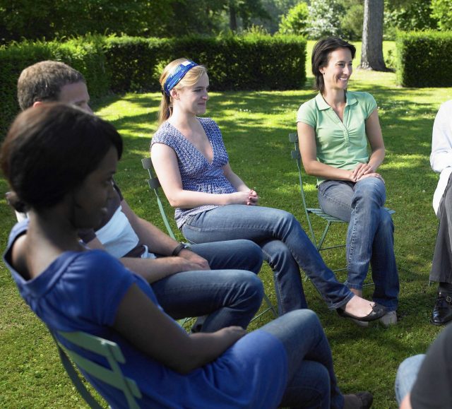 Gruppe bei Outdoor-Gesprächsrunde im Grünen.