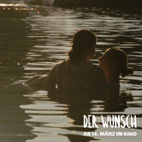 Zwei Personen umarmen sich im Wasser bei Sonnenuntergang.